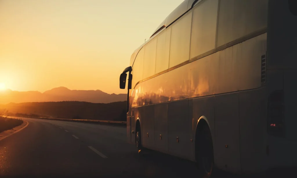 bus driving on road towards the setting sun