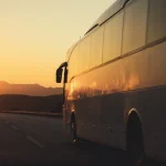 bus driving on road towards the setting sun
