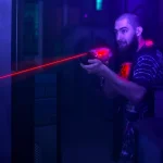 laser tag game player shooting light gun science fiction vest in black light